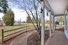 Looking out on tranquil Mechums River Road, the front porch has attractive white pillars and brick edging for a classic feel. A winding walkway leads from the front entrance to the driveway. 