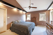 Sweeping vaulted ceilings rise over the master bedroom. The room has two closets, including a walk-in. Recessed lighting mounted on both walls gives the room a modern feel. The door on the left leads to an unfinished attic with great potential. 