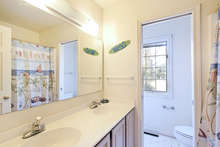 This full bath has a long vanity with double sinks and wood cabinets, as well as a tub shower. 