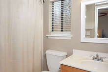 The attached master bathroom has a tub shower and vinyl flooring. 